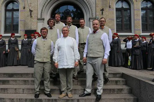 Kora vīri tautastērpos uz kāpnēm pirms gājiena
